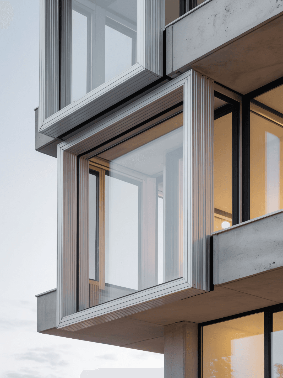 Modern building facade with protruding corner window design and aluminum framing.